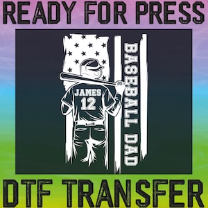 May include: A black and white design of a baseball player with a bat, wearing a jersey with the name "JAMES" and the number "12" on it. The player is standing in front of an American flag with the words "BASEBALL DAD" written vertically on the right side of the flag. The text "READY FOR PRESS" is at the top of the image and the text "DTG TRANSFER" is at the bottom of the image.