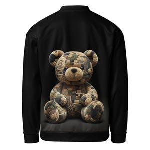 May include: Black bomber jacket featuring a large teddy bear design on the back. The bear is made of various fabric patches in shades of brown, green, and tan. The jacket has a classic bomber style with a ribbed collar and cuffs.