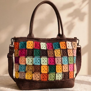 May include: A tote bag featuring a multi-colored granny square crochet pattern in shades of yellow, orange, pink, teal, and brown. The bag includes dark brown leather-like handles, a matching detachable shoulder strap, and a solid brown base.