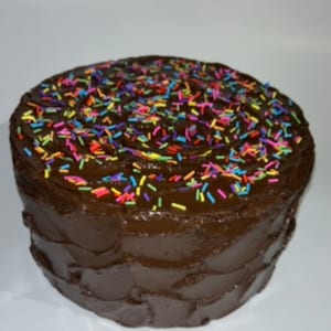 以下が含まれることがあります： チョコレートケーキは、チョコレートのフロスティングで覆われ、カラフルなスプリンクルで飾られています