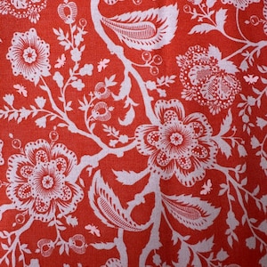 May include: Red fabric with a white floral pattern. The pattern features stylised flowers, leaves, and berries.