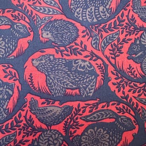 Puede incluir: Un patrón repetitivo con animales estilizados del bosque, incluyendo un oso, una ardilla y un conejo, en una combinación de colores azul marino y gris. Los animales se destacan sobre un fondo rojo vibrante con acentos de hojas, creando un diseño caprichoso.