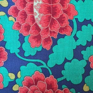 May include: A fabric pattern featuring large, layered red peony-like flowers with light-coloured centres, surrounded by vibrant green, cloud-shaped leaves on a deep navy blue background. The design includes small yellow accents scattered throughout.