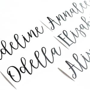 May include: Four names written in black cursive script on white paper: Madeline, Odelia Annalee, Elizabeths, and Alix.