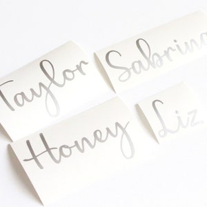 May include: Four silver vinyl stickers with names written in cursive: Taylor, Sabrina, Honey, and Liz.