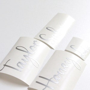 May include: Three white labels with silver lettering. The labels read "Taylor", "Honey", and "Sophia".