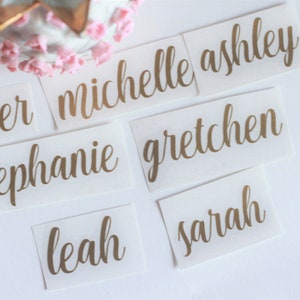 May include: Six gold foil name tags with the names Amber, Michelle Ashley, Stephanie, Gretchen, Leah, and Sarah.