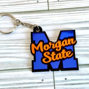 Op de afbeelding: Een blauwe en zwarte sleutelhanger met een grote "M" en de tekst "Morgan State" in oranje letters.