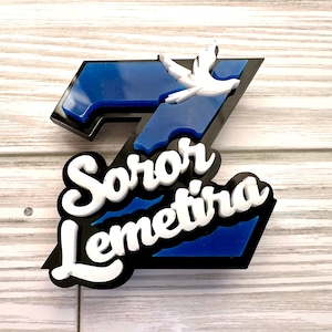 Peut inclure: Un panneau 3D bleu et noir avec le texte "Soror Lemetira" en lettres blanches. Une colombe blanche vole au-dessus du texte.