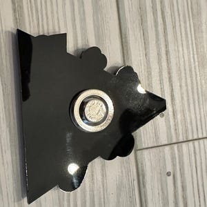 Op de afbeelding: Zwart-witte cartoon-personage magneet met een zilveren magnetische achterkant. De magneet is gevormd als een huis met een puntdak.