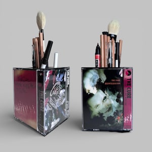 May include: A set of three ceramic mugs with a speckled, matte finish. The mugs are in shades of cream, light gray, and dark gray. Each mug has a simple, minimalist design and a rounded handle.