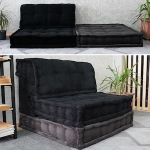 Puede incluir: Un sof&aacute; modular de terciopelo negro con tres cojines. El sof&aacute; est&aacute; formado por dos piezas separadas que se pueden organizar en diferentes configuraciones. El sof&aacute; est&aacute; sobre una alfombra gris.