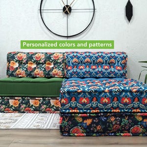 Puede incluir: Asientos modulares con cojines estampados florales y geométricos en tonos verdes, azules y naranjas. El texto "Colores y patrones personalizados" se muestra en una pancarta verde. Los asientos están sobre una alfombra blanca.