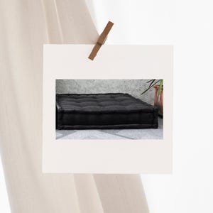 Puede incluir: Un coj&iacute;n de suelo rectangular de terciopelo negro con botones acolchados. El coj&iacute;n es grueso y c&oacute;modo.