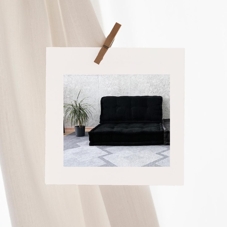 Puede incluir: Un sof&aacute; fut&oacute;n negro con una alfombra gris debajo. El fut&oacute;n est&aacute; en una habitaci&oacute;n con una pared blanca y una planta en una maceta.