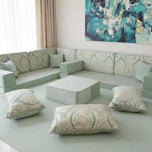 May include: A sectional sofa with matching pillows and a coffee table. The furniture is light green with a patterned design. The pillows are scattered on a light green rug.