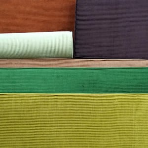 May include: A collection of corduroy fabric swatches featuring a variety of colors including rust orange, deep purple, light mint green, soft pink, vibrant emerald green, and chartreuse yellow, all displaying a distinct vertical ribbed texture.
