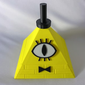 May include: A yellow pyramid-shaped object with a black top and a black bow tie. The pyramid features a large eye with a white iris and black eyelashes. The object is likely a decorative item or a toy.
