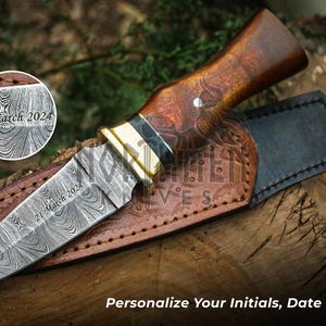 May include: A brown-handled,  damascus steel dagger with a leather sheath. The blade is engraved with the date "21 March 2024".