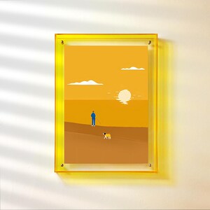 Peut inclure: Une impression d'art encadr&eacute;e repr&eacute;sentant un paysage minimaliste. L'&oelig;uvre d'art repr&eacute;sente une personne avec un chien sur une surface marron, avec un soleil couchant et des nuages en arri&egrave;re-plan. Le cadre est de couleur jaune vif.
