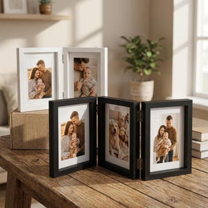 Op de afbeelding: Een collectie scharnierende fotolijsten in wit en zwart, met familiefoto's. De lijsten zijn gemaakt van hout en hebben een eenvoudig, modern ontwerp. De foto's tonen gezinnen met baby's en een hond.