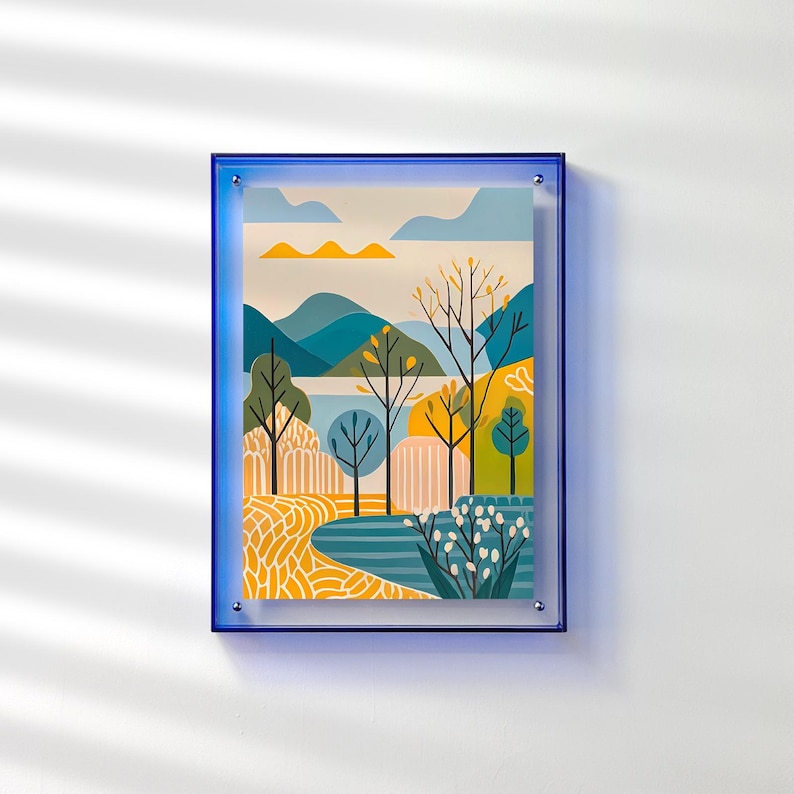 Peut inclure: Une impression d'art encadr&eacute;e repr&eacute;sentant un paysage illustr&eacute; avec une sc&egrave;ne naturelle. L'&oelig;uvre d'art pr&eacute;sente des arbres, des montagnes et de l'eau dans des tons de bleu, jaune et vert. L'impression est encadr&eacute;e dans un cadre bleu vif.