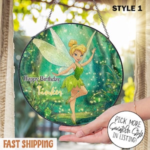Puede incluir: Un atrapasoles redondo de vidriera con Tinkerbell, vestida con un vestido y alas verdes, sobre un fondo verde y azul. Se muestra el texto "Happy Birthday Tinker". Tiene una cadena para colgar.