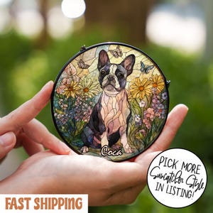 May include: Round stained glass suncatcher featuring a Boston Terrier dog surrounded by flowers and butterflies. The dog is black and white, with the name "Coca" written below. The suncatcher has a black metal frame.