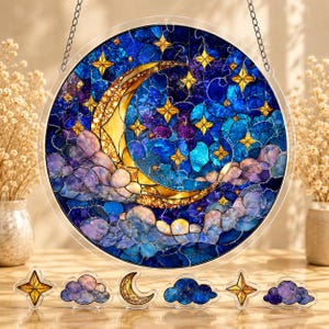 May include: A circular stained glass suncatcher featuring a crescent moon and golden stars against a deep blue and purple night sky with clouds. The piece hangs from a silver chain and is accompanied by six smaller, separate matching ornaments.