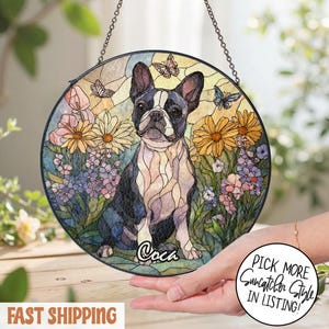 May include: Round stained glass suncatcher featuring a Boston Terrier dog surrounded by flowers and butterflies. The dog is black and white, with the name "Coca" below. The suncatcher hangs from a chain.