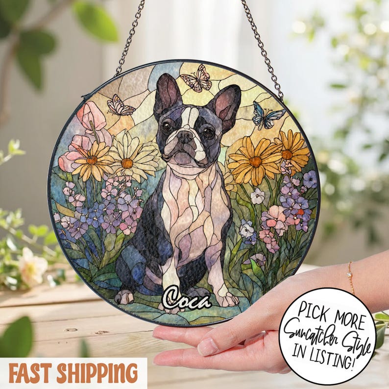 May include: Round stained glass suncatcher featuring a Boston Terrier dog surrounded by flowers and butterflies. The dog is black and white, with the name "Coca" below. The suncatcher hangs from a chain.