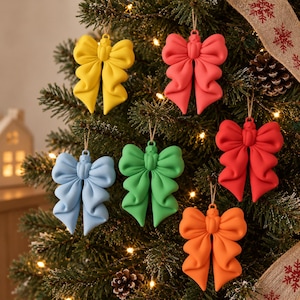 Può includere: Un set di sei decorazioni a forma di fiocco con finitura opaca in giallo, corallo, azzurro, verde, rosso e arancione. Ogni fiocco presenta una texture liscia e scolpita con un piccolo occhiello sulla parte superiore per appenderlo all'albero.