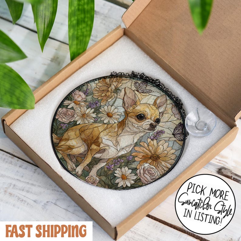 May include: A round stained glass suncatcher featuring a Chihuahua dog surrounded by flowers and butterflies. The suncatcher is in a black metal frame and comes with a suction cup for hanging. The suncatcher is packaged in a cardboard box.