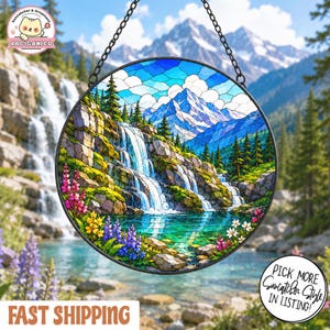 May include: A circular stained glass suncatcher featuring a mountain landscape with a cascading waterfall, a turquoise pool, evergreen trees, and colorful wildflowers. The piece is framed in black metal and hangs from a black chain.