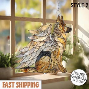 May include: A stained glass suncatcher shaped like a German Shepherd dog with large feathered wings. The dog is rendered in shades of amber, brown, and black glass with dark lead lines. The text STYLE 2 is visible in the upper right corner.