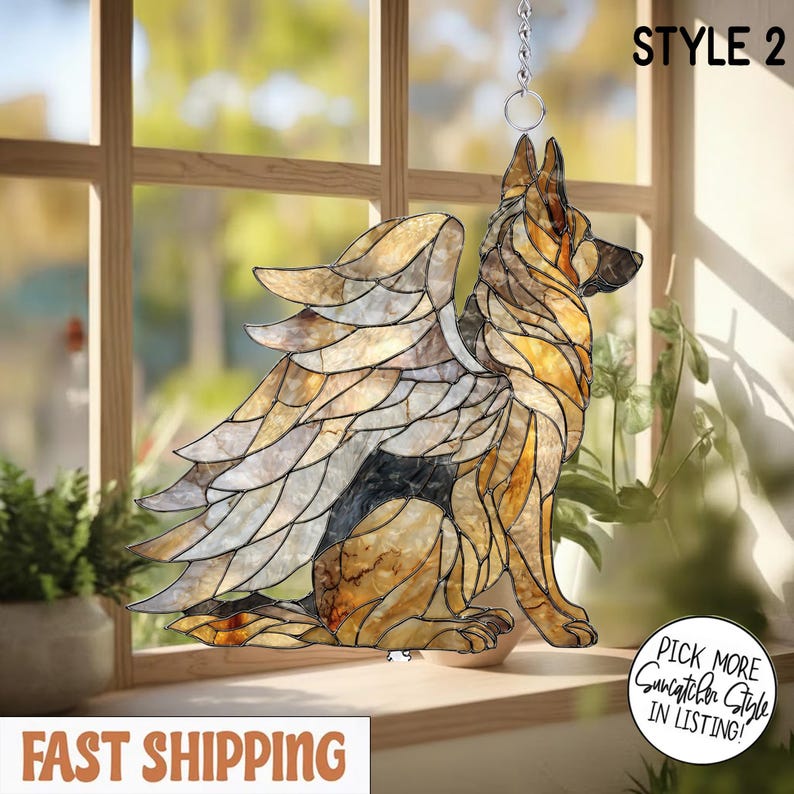 May include: A stained glass suncatcher shaped like a German Shepherd dog with large feathered wings. The dog is rendered in shades of amber, brown, and black glass with dark lead lines. The text STYLE 2 is visible in the upper right corner.