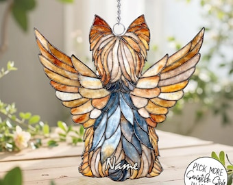 May include: A stained glass suncatcher shaped like a dog with wings, featuring amber, brown, and blue glass pieces held together by dark metal solder. The piece includes a silver metal chain for hanging and the word Name written in white script.