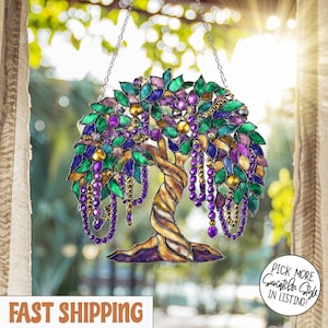 Op de afbeelding: Gebrandschilderde boom zonnevanger met groene, paarse en gouden accenten. De boom heeft een gedraaide bruine stam en hangende paarse kralenkettingen. De zonnevanger hangt aan een ketting.