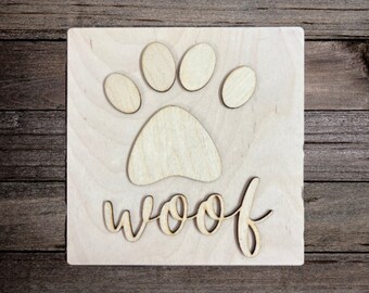 May include: Wooden sign with a paw print and the word "woof" in a decorative font.