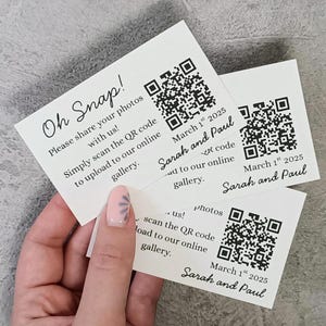 May include: White cards with the text "Oh Snap!" and instructions to share photos via a QR code. Each card includes the date "March 1st 2025" and the names "Sarah and Paul".