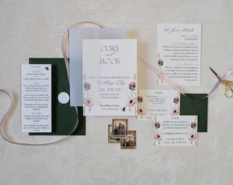 Puede incluir: Conjunto de invitaciones de boda con detalles florales. El conjunto incluye una invitación, una tarjeta de confirmación de asistencia, una tarjeta de detalles y un menú. La invitación presenta los nombres "Clara y Jacob" y la fecha de la boda. Cinta lila clara y tijeras doradas.