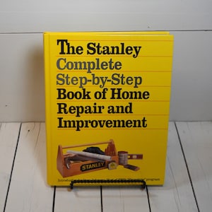 May include: A yellow book titled "The Stanley Complete Step-by-Step Book of Home Repair and Improvement". The cover features a toolbox with tools and the Stanley logo.