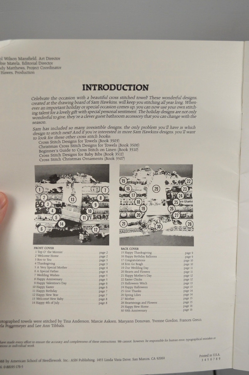 May include: A page from a cross-stitch pattern book. The page features an introduction, a list of designs, and a diagram of various cross-stitch patterns. The book includes designs for towels, baby bibs, and Christmas ornaments.