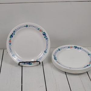May include: Set of six white ceramic dinner plates with a blue, green, and pink floral pattern around the rim.