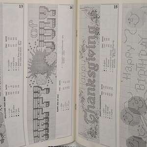 May include: A book page featuring cross-stitch patterns. Designs include "WELCOME NEW BABY", "HAPPY 4TH OF JULY", "HAPPY THANKSGIVING", and "HAPPY BIRTHDAY". Each design is accompanied by a color key and DMC floss numbers.