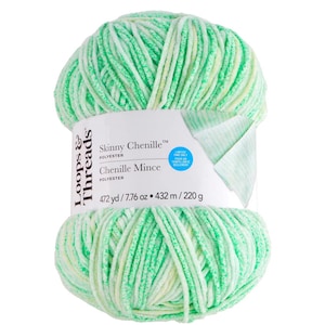 May include: A ball of green and white chenille yarn, labelled "Skinny Chenille" and "Chenille Mince". The label indicates 432 m of yarn, weighing 220 g. The yarn is made of polyester and is from the brand "Loops & Threads".