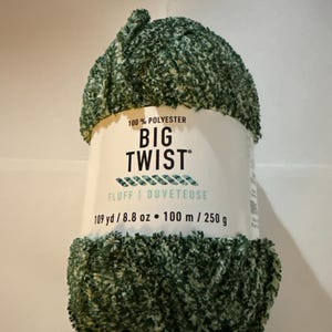 May include: A ball of green and white Big Twist Fluff yarn. The label reads "100% Polyester" and "109 yd / 8.8 oz". The yarn is a fluffy, textured material, ideal for knitting or crocheting projects.