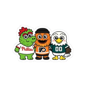 Könnte beinhalten: Ein Aufkleber mit drei Cartoon-Maskottchen: einem grünen Wesen mit einem Phillies-Trikot, einem orangefarbenen Wesen mit einem Flyers-Trikot und einem weißen Adler mit einem Eagles-Trikot. Die Maskottchen lächeln und stehen zusammen.