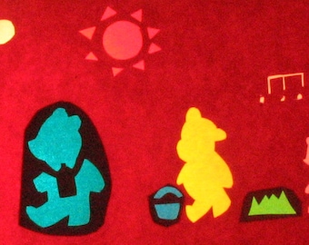 May include: A red felt background with a row of colorful felt cutouts of bears. The bears are wearing different colored shirts and have different colored pants. There is a yellow sun in the top center of the image.
