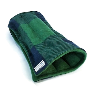 May include: A green and navy blue plaid fabric dog bed with a fleece lining. The bed is shaped like a tunnel and has a label that says "Therapeutic".